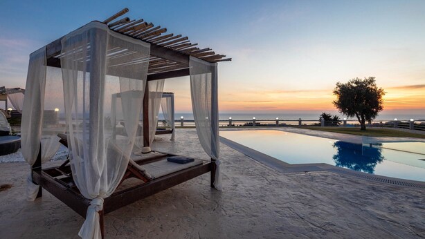 A serene outdoor setting with a wooden canopy bed, a pool, and a sunset view. - Villa Mediterranean View (Corfu)