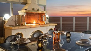 A dining area with a brick fireplace, outdoor seating, and a sunset view. - Villa Mediterranean View (Corfu)