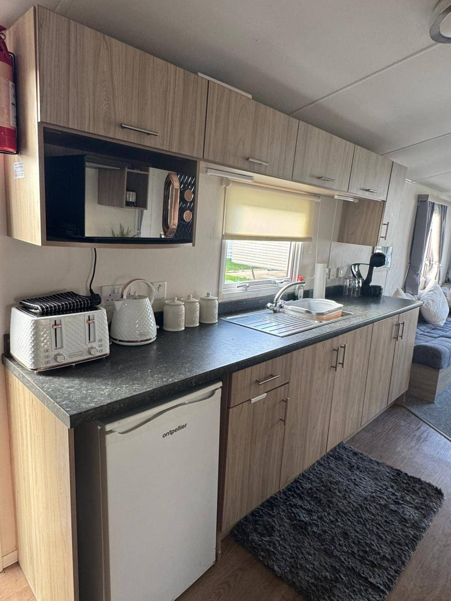 A compact kitchen with a toaster, kettle, and a sink.