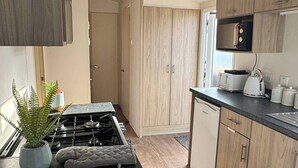 Una cocina moderna con armarios de madera, una estufa a gas, un microondas y un lavavajillas.