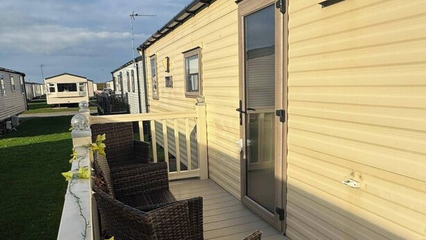 Una hilera de casas móviles con terraza de madera y muebles de mimbre.