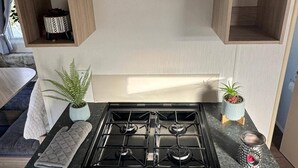 Una cocina compacta con estufa a gas, horno y campana extractora de acero inoxidable.