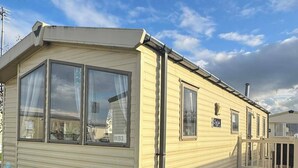 Una casa móvil con un ventanal grande, un porche pequeño y el número 'N193' a la vista.