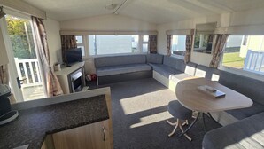 A cozy RV interior with a sofa, a small table, a TV, and a kitchen area.