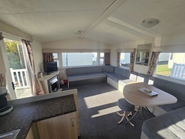 A cozy RV interior with a sofa, a small table, a TV, and a kitchen area.