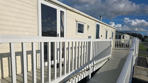 A row of mobile homes with white railings and a wooden deck.