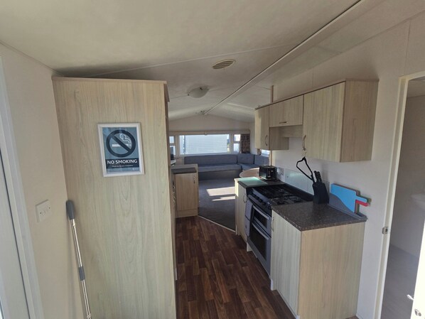A compact RV kitchen with wooden cabinets, a gas stove, and a toaster. - Patricia 3 Bed Balcony in Rhyl (Rhyl)