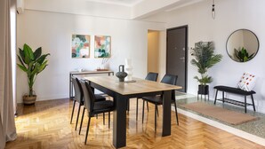A dining area with a wooden table, black chairs, and a bench. There are potted plants and artwork on the walls. - Home of Petros | Near Plaka - Temple of Zeus View (Athens)