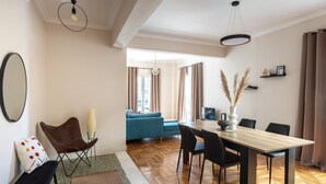 A modern living room with a wooden herringbone floor, a dining table with chairs, a sofa, and a coffee table. - Home of Petros | Near Plaka - Temple of Zeus View (Athens)