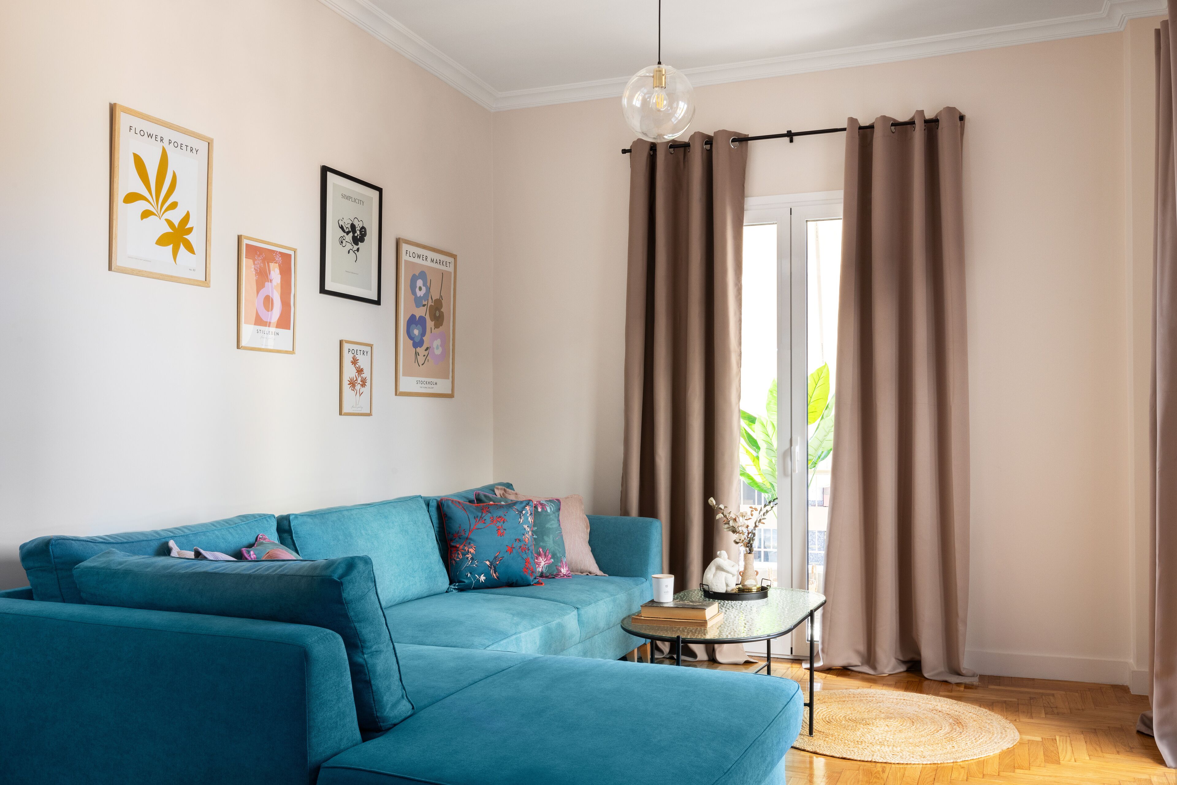 Una sala de estar con un sofá color turquesa, una mesita de centro y un ventanal con cortinas.