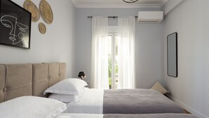 A bedroom with a bed, a headboard, a window with curtains, and a wall-mounted air conditioner. - Home of Petros | Near Plaka - Temple of Zeus View (Athens)