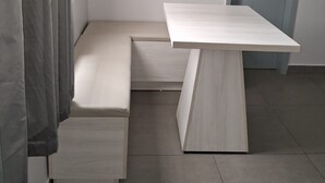 Une pièce minimaliste avec un banc intégré, une petite table, une porte et un interrupteur sur le mur.