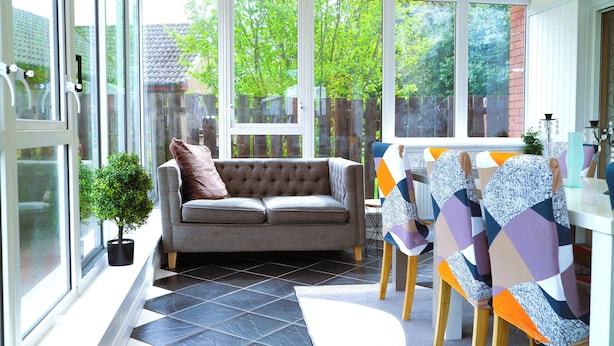 A modern living room with a grey sofa, a small potted plant, and a dining area with patterned chairs and a white table. - Edinburgh Mansion Retreat (Edinburgh)