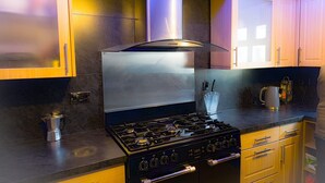 A kitchen with a stainless steel stove, wooden cabinets, and a coffee maker. - Edinburgh Mansion Retreat (Edinburgh)