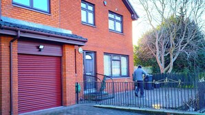 A red brick building with a closed red garage door, a gated entrance, and a metal fence. - Edinburgh Mansion Retreat (Edinburgh)