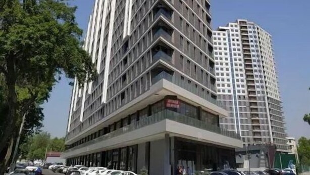 Un edificio alto y moderno con un diseño angular distintivo, que cuenta con varios balcones y un área de entrada destacada.
