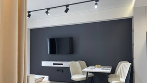 Un comedor moderno con una pared oscura, un televisor montado y una decoración de mesa minimalista.