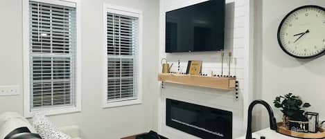 Una cocina moderna con un televisor de pantalla plana, un reloj y un lavamanos.