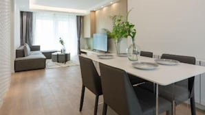 Ein moderner Essbereich mit einem weißen Tisch, schwarzen Stühlen und einer hängenden Leuchte.