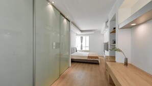 Ein modernes Schlafzimmer mit Bett, Nachttisch, Fernseher und einer Schiebetür.