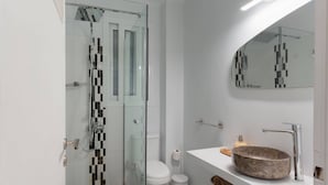A modern bathroom with a glass shower enclosure, a white toilet, and a sink with a stone basin. - Phaedrus Living Kolonaki Maple Residence (Athens)