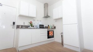 A modern kitchen with white cabinets, a stainless steel range hood, a microwave, and an oven. - Flat 310 beautiful one bed apartment (Smethwick)