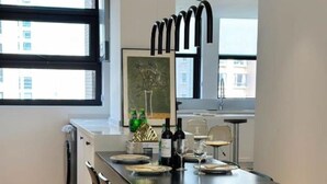 Ein moderner Essbereich mit einem rechteckigen Tisch, Metallstühlen und einer hängenden Leuchte.