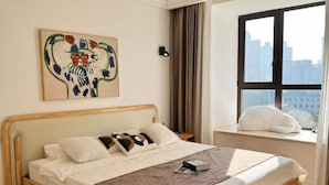 Ein Schlafzimmer mit einem hölzernen Bett, Blick auf die Stadt durch ein großes Fenster, einem Gemälde an der Wand und einer Deckenleuchte.