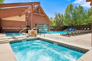 A pool area with a hot tub, lounge chairs, and a wooden building structure. - Across From Ski Lift, Hiking. Walk to Town. (Breckenridge)