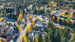 Vue aérienne d’un quartier résidentiel, avec un immeuble imposant clairement identifiable comme un immeuble d’appartements, entouré d’arbres et d’autres maisons.