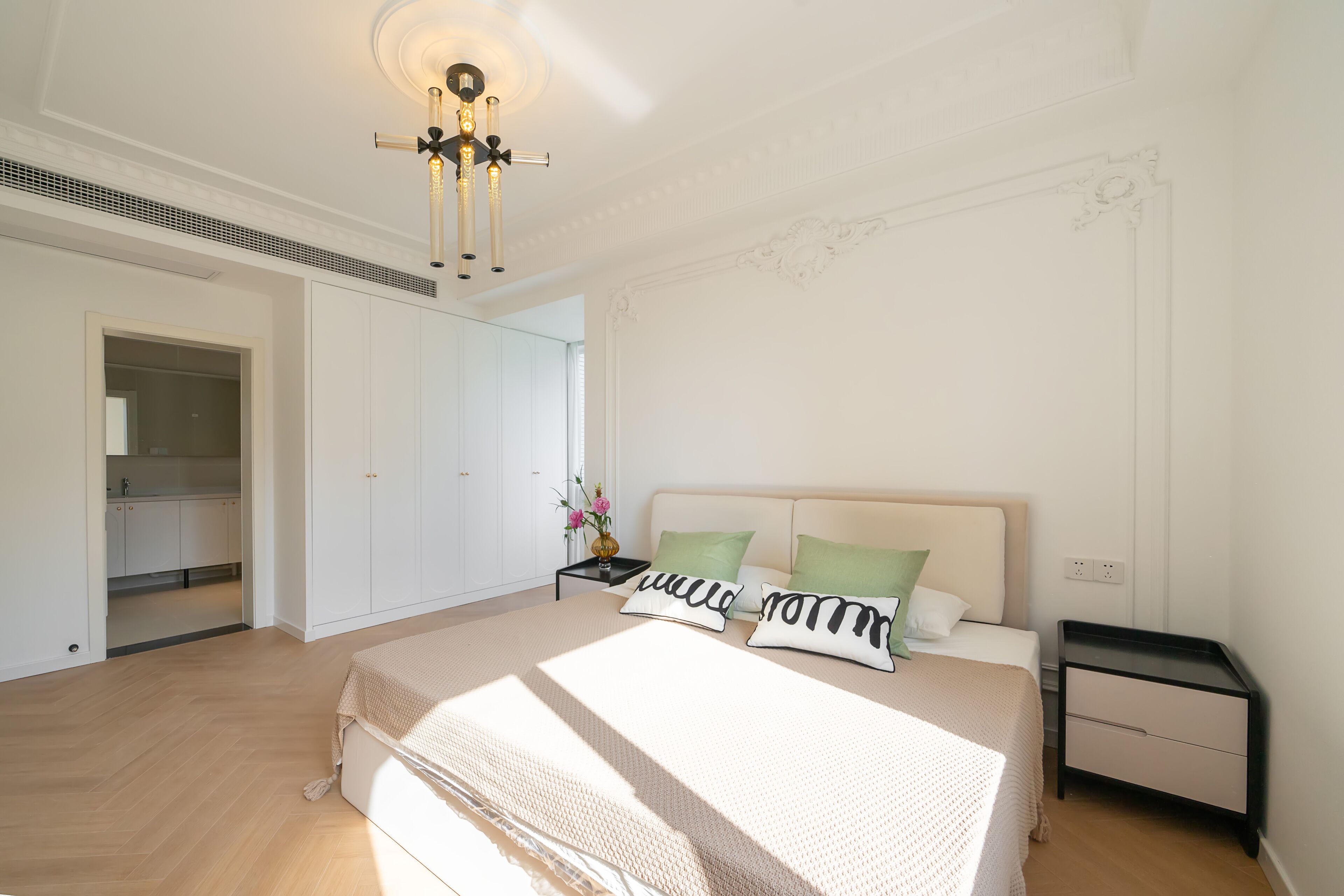 Quarto com uma cama grande, mesa de cabeceira, cômoda e luminária no teto.