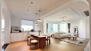 Ein geräumiger Wohnbereich mit Esstisch, Sofa und großem Fenster.