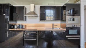 Cozinha moderna com eletrodomésticos de aço inoxidável, uma ilha central e vista pela janela.