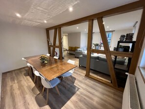 A modern dining area with a wooden table and chairs, a sofa, and a radiator.