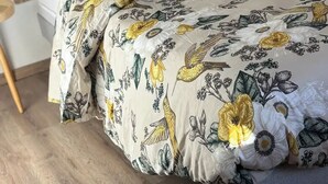 A bed with a woven headboard, a floral-patterned duvet, and a matching pillow.