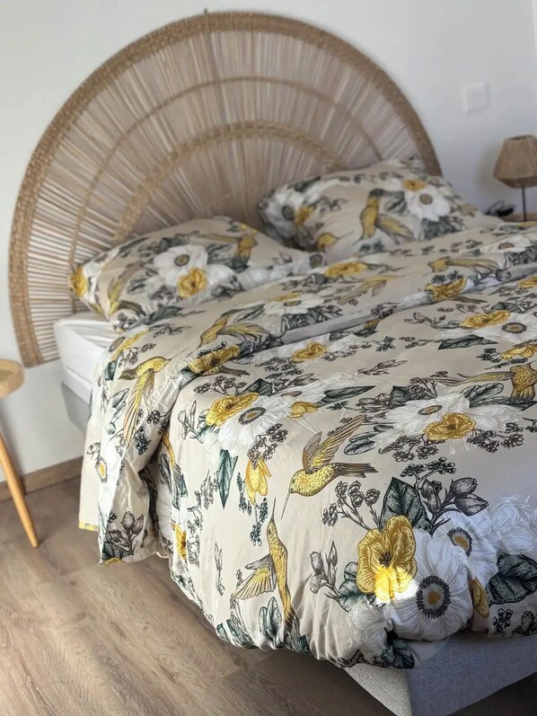A bed with a woven headboard, a floral-patterned duvet, and a matching pillow.