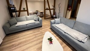 A modern living room with two grey sofas, a white coffee table, and wooden flooring.