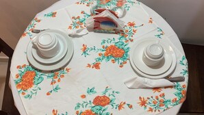 A round table with two white teapots, two white cups, and two white saucers, set on a floral tablecloth. - Recanto da Cleide (Paraty)