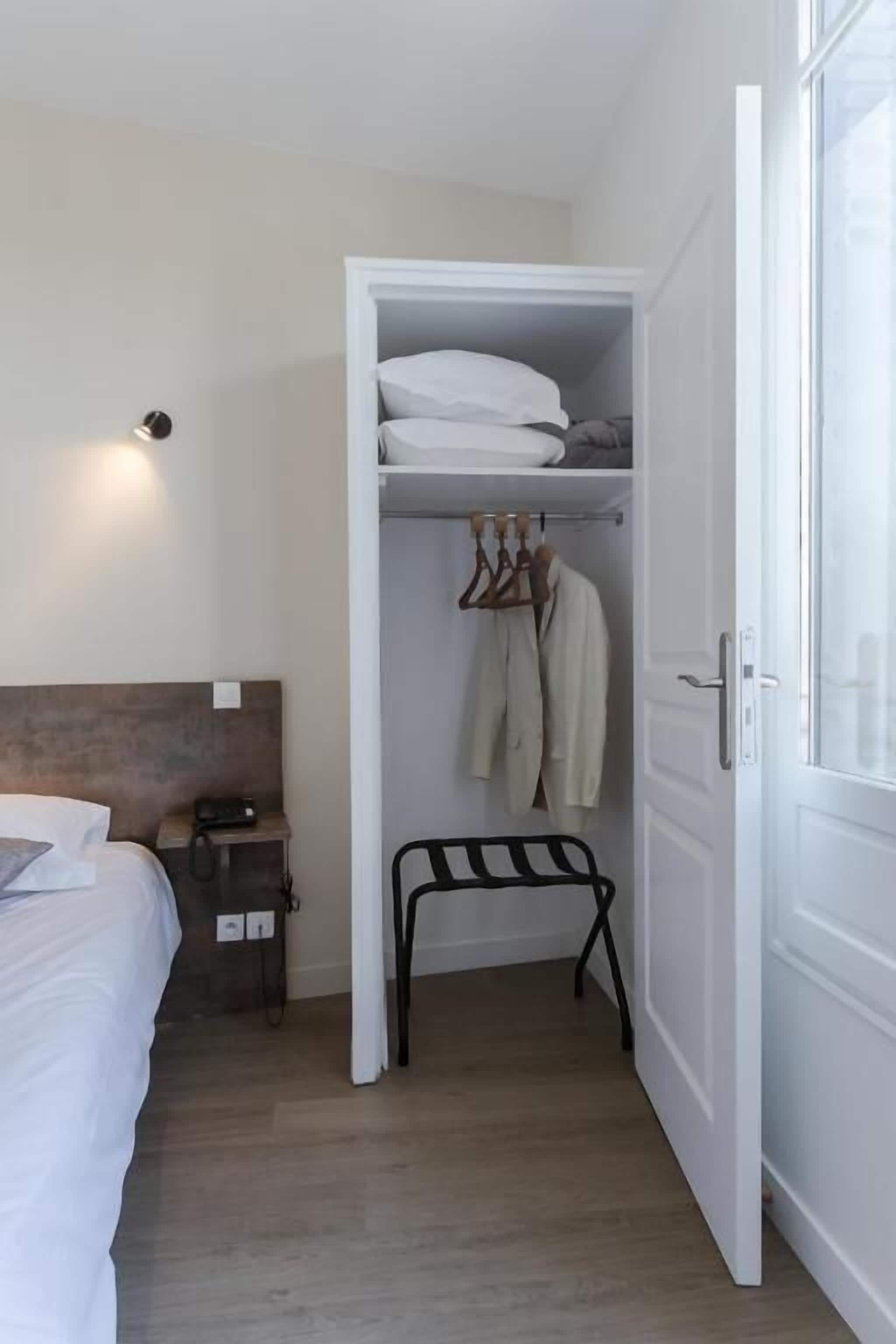 Camera da letto con un letto, un comodino e un armadio pieno di abiti.