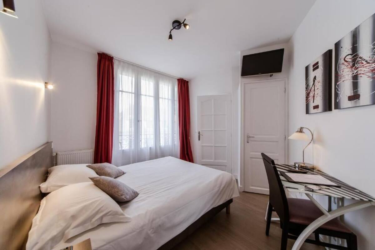 A bedroom with a bed, a desk, and a chair.