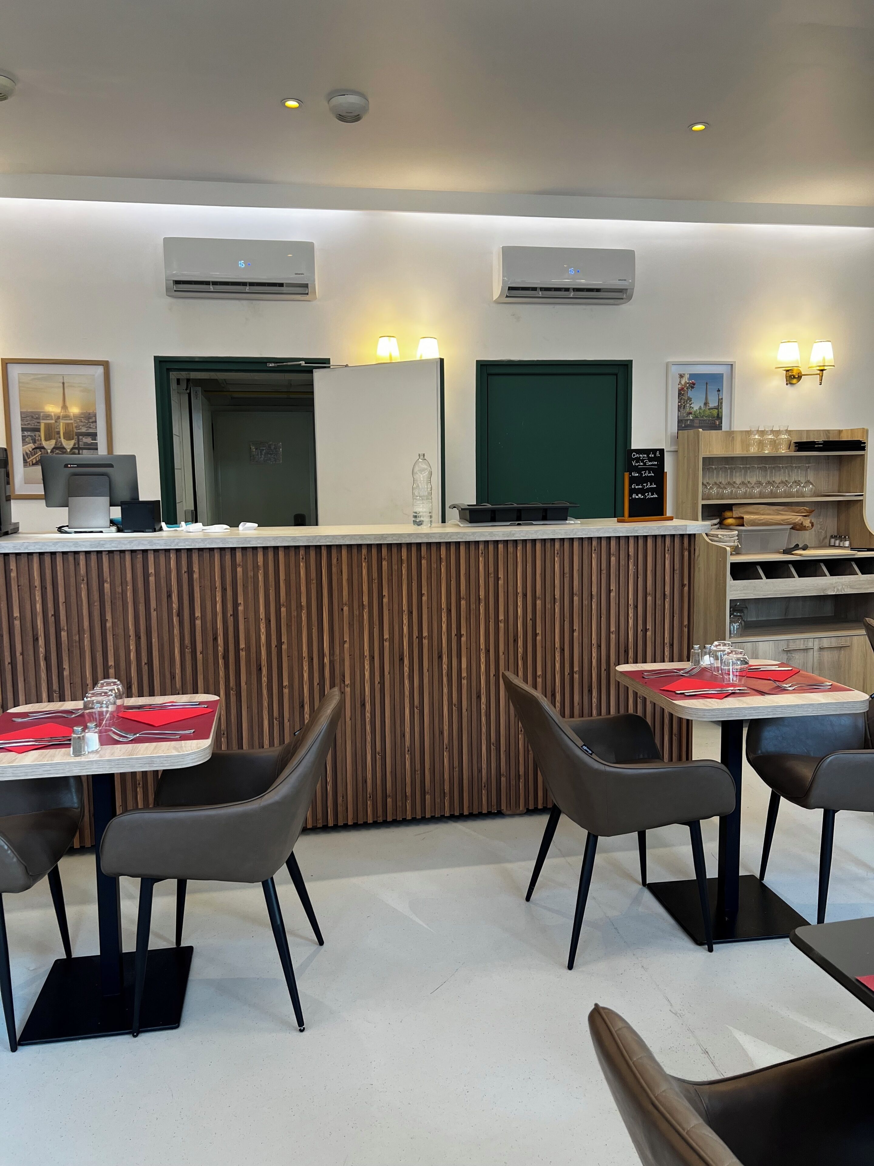 En restaurant med en trædisk, to borde med stole og en menutavle.