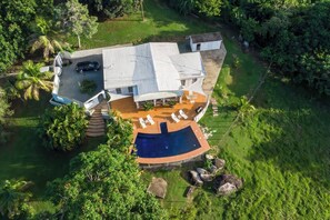 Une maison avec une piscine, un patio couvert et une voiture garée devant.