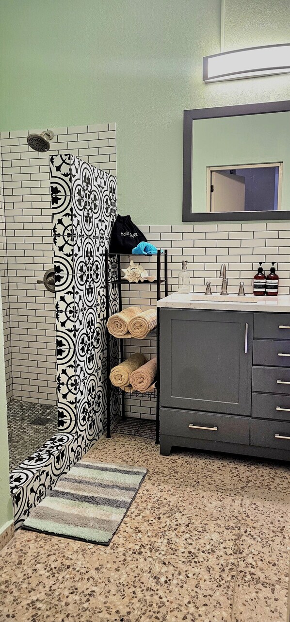 A bathroom with a patterned shower curtain, a sink with toiletries, and a dark cabinet.