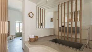 Une salle de bain moderne avec une grande baignoire, des éléments décoratifs en bois, un miroir et un panier en osier contenant des serviettes.