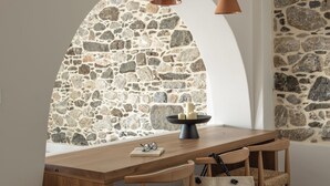 Un coin repas avec un mur en pierre, une table en bois et des chaises.