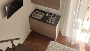 Μια μικρή, λειτουργική κουζίνα με εντοιχισμένη κουζίνα, νεροχύτη και έναν μικρό πάγκο εργασίας.