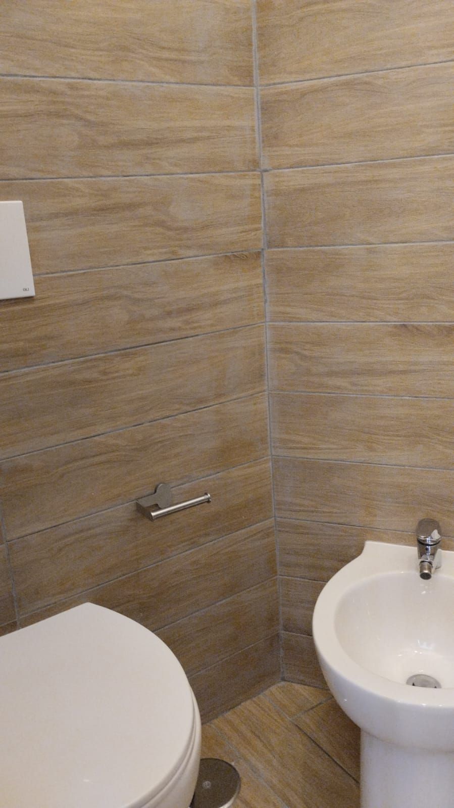 Ein Badezimmer mit Toilette, Bidet und gefliesten Wänden.
