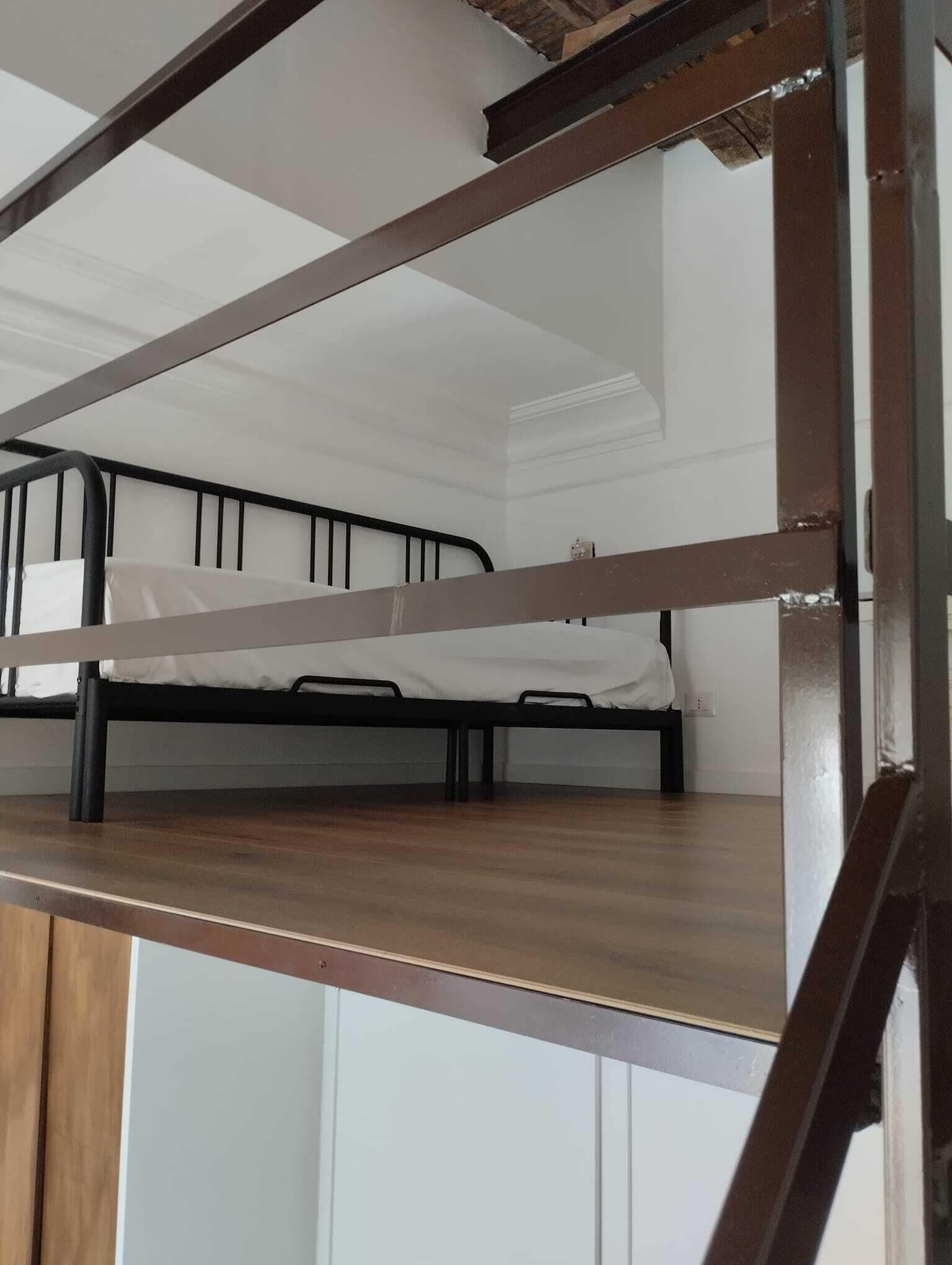 A bunk bed with a wooden platform and metal frame, white walls, and a white ceiling.