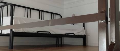A bunk bed with a wooden platform and metal frame, white walls, and a white ceiling.