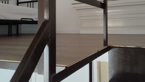 Ένας μοντέρνος εσωτερικός χώρος με μια μεταλλική σκάλα, ένα κρεβάτι και έναν λευκό τοίχο.